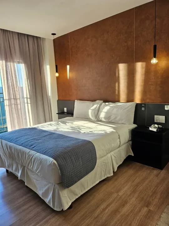 Quarto com cama de casal e parede acobreada