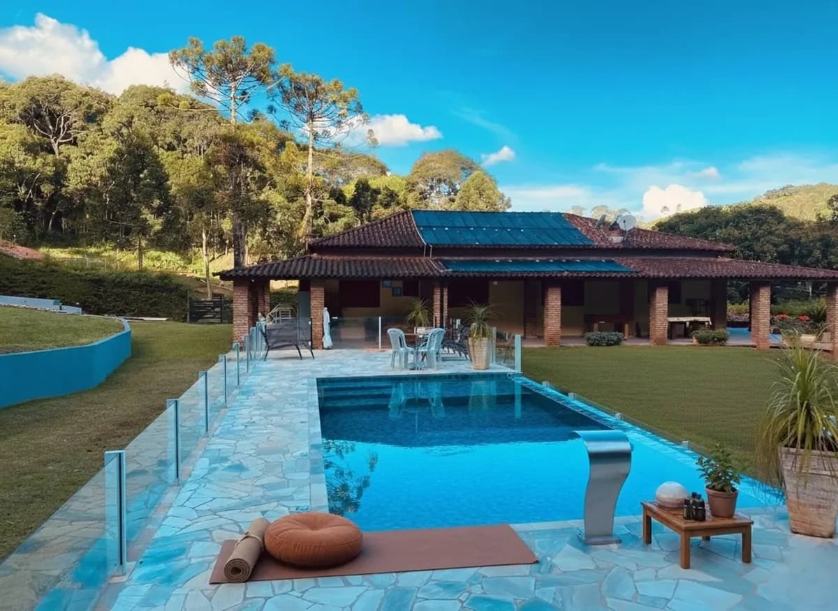 Piscina de borda infinita com a casa e a serra ao fundo em Joanópolis