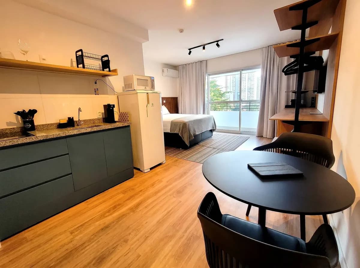 Studio integrado no Butantã com cozinha, mesa redonda e cama junto à varanda