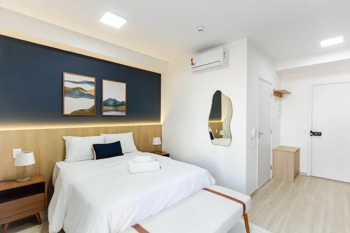 Cama de casal com painel azul-marinho no studio do Campo Belo, São Paulo