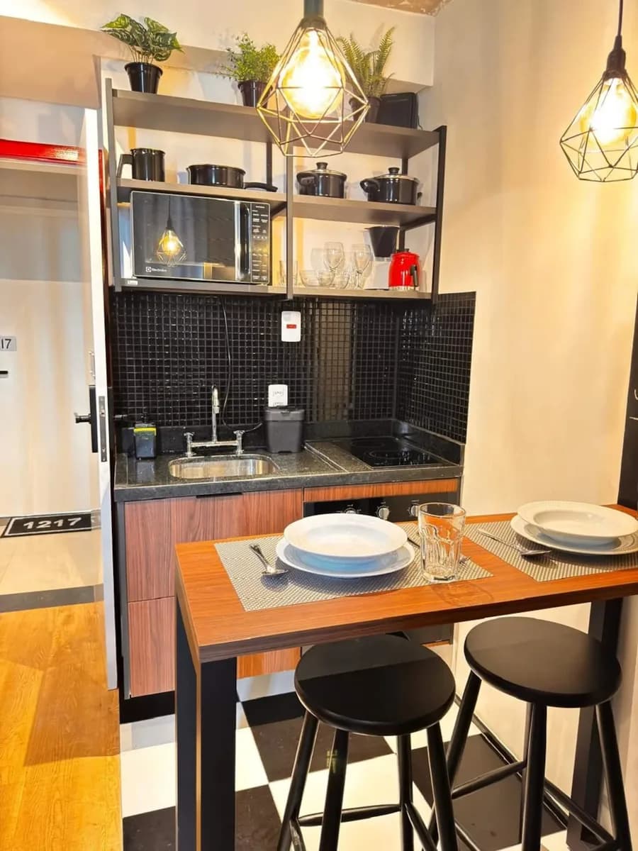 Cozinha em estilo industrial com mesa alta posta para dois no studio da Consolação, São Paulo